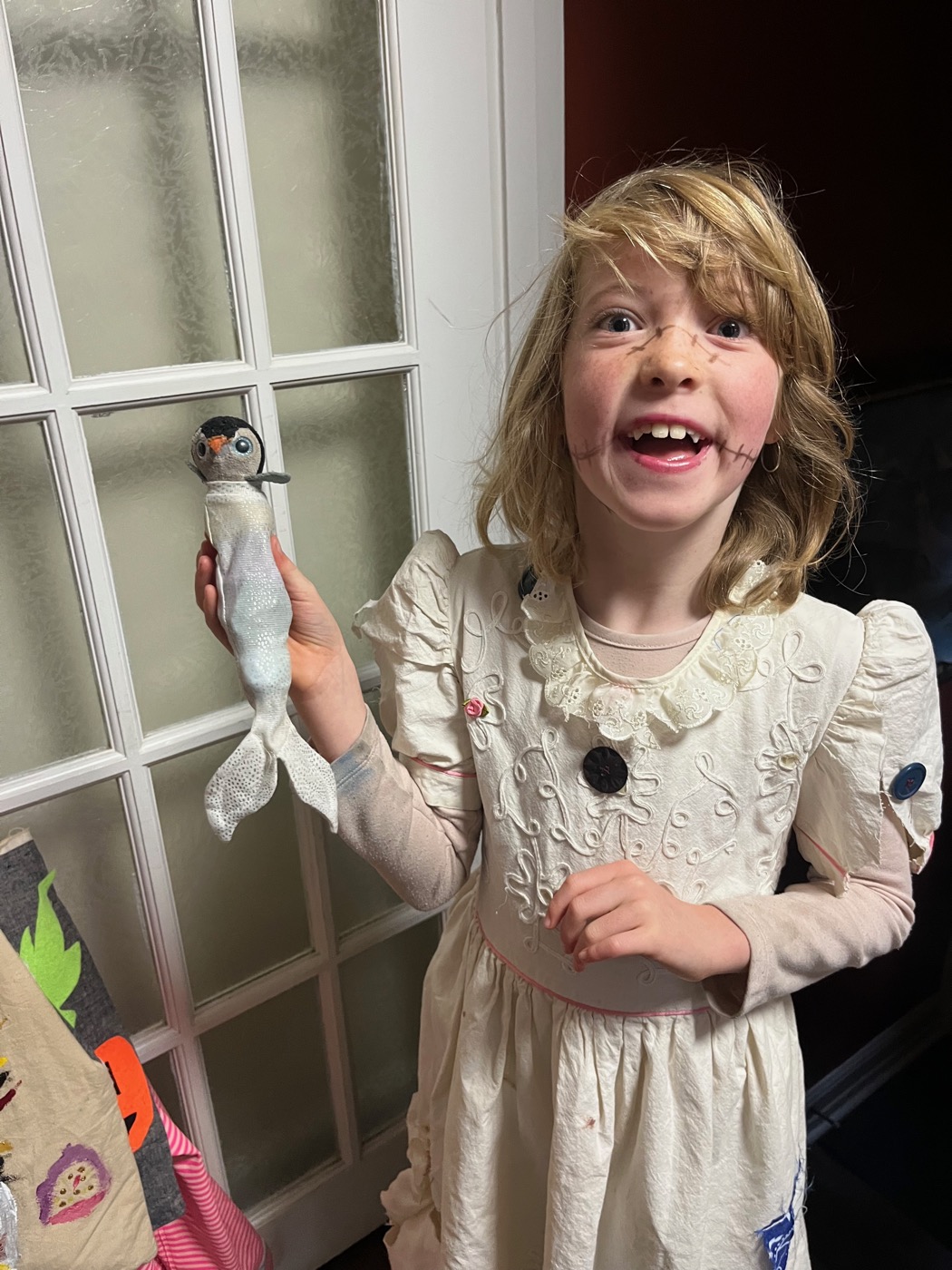 Beatrix in costume holding up Pengi dressed as a merman